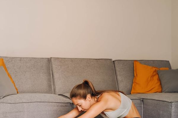 A person stretching indoors in a calm, focused environment.